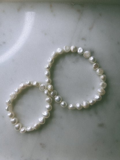 Two pearl hair ties on a marble surface