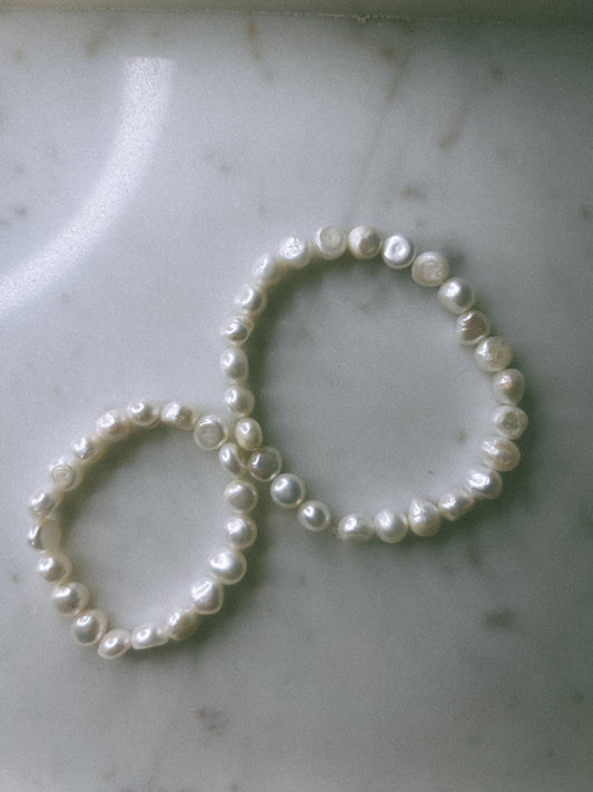 Two pearl hair ties on a marble surface